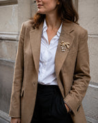 Gold-tone freshwater pearl bow brooch styled on a camel blazer with a white shirt