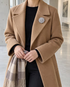 Lumi silver-tone snowflake brooch at approximate true scale on a camel coat lapel