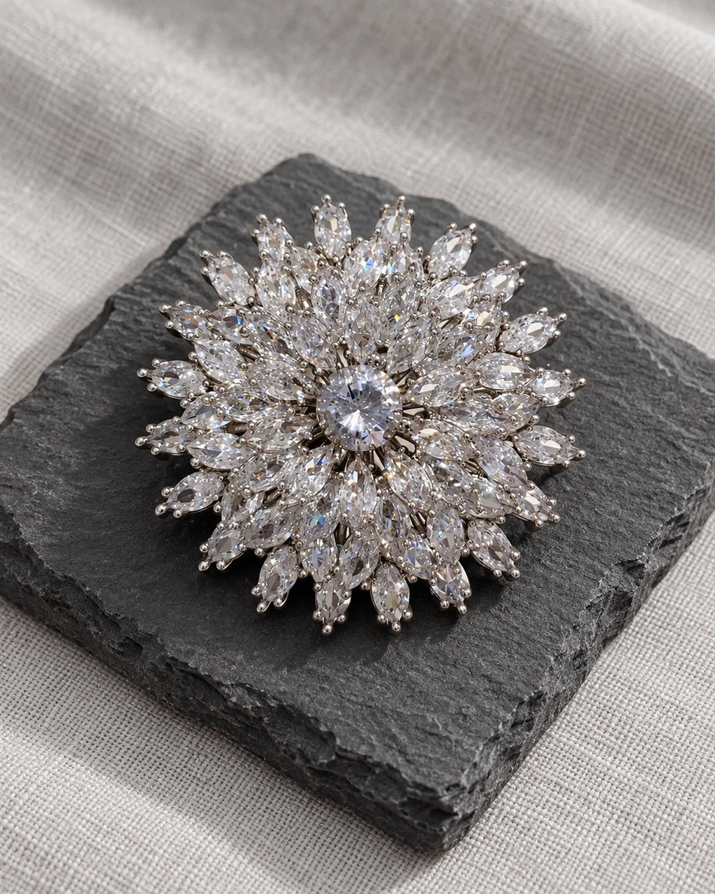 Lumi silver-tone snowflake brooch on dark slate with pale linen