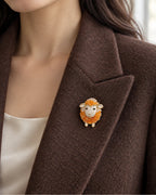 Orange crystal sheep brooch worn on a brown blazer lapel