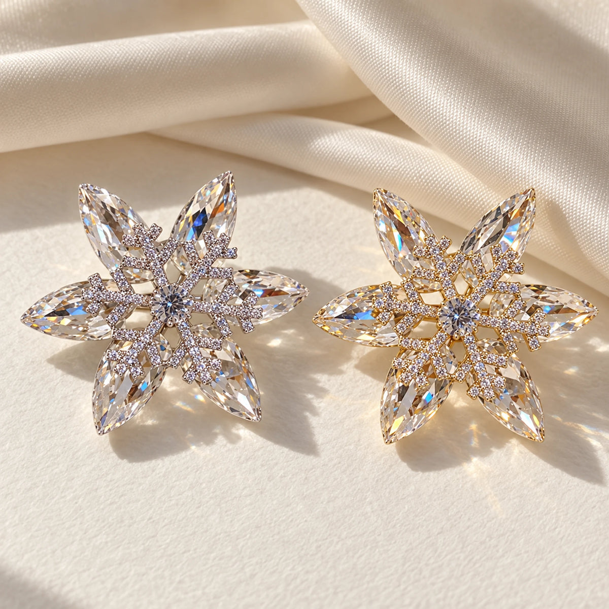 Nive snowflake brooch in Silver and Gold finishes, side by side on ivory paper.
