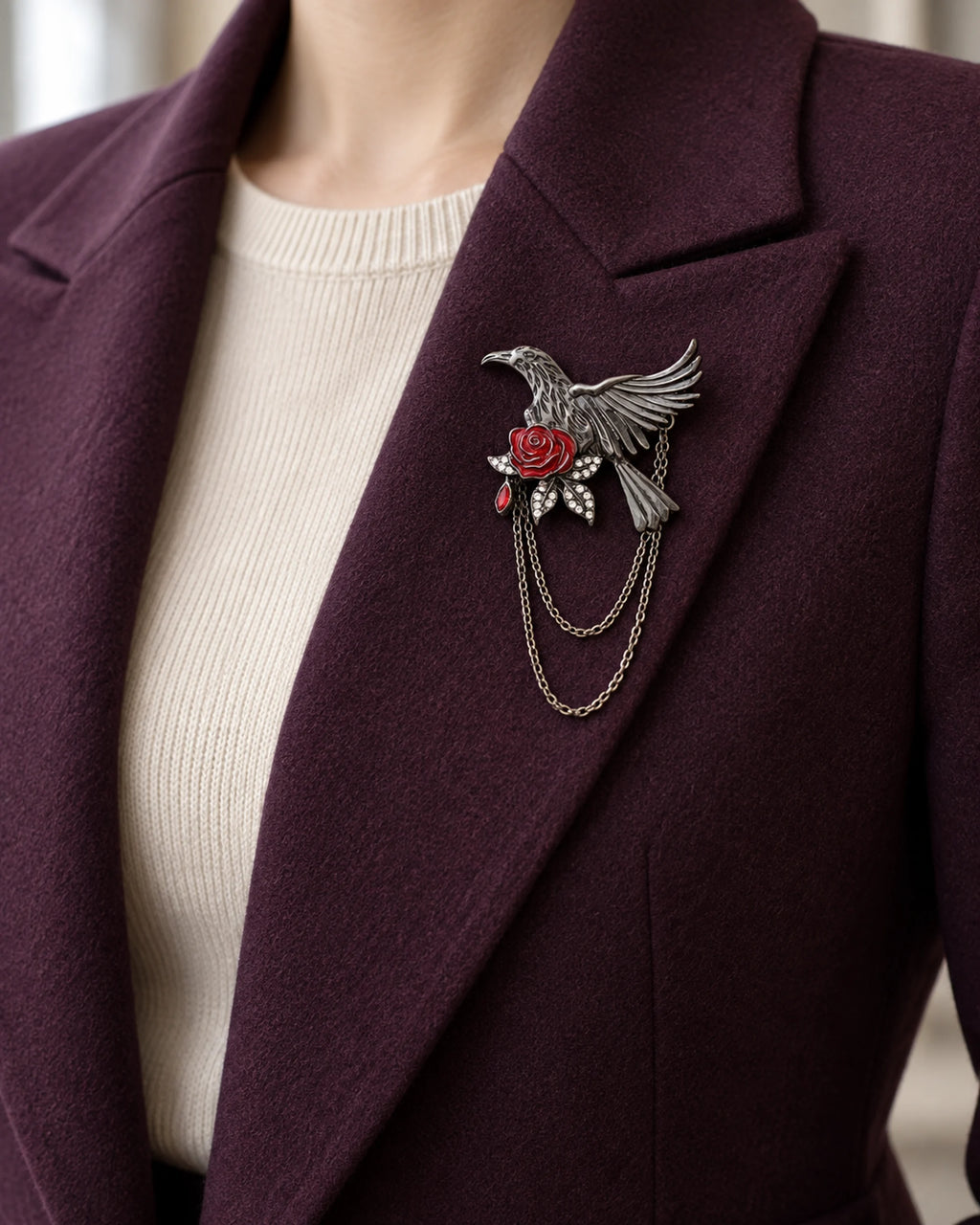 Noctra bird and rose chain brooch pinned within a plum blazer lapel