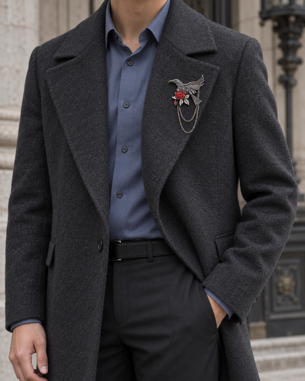 Noctra bird and rose brooch on a charcoal coat over a blue shirt