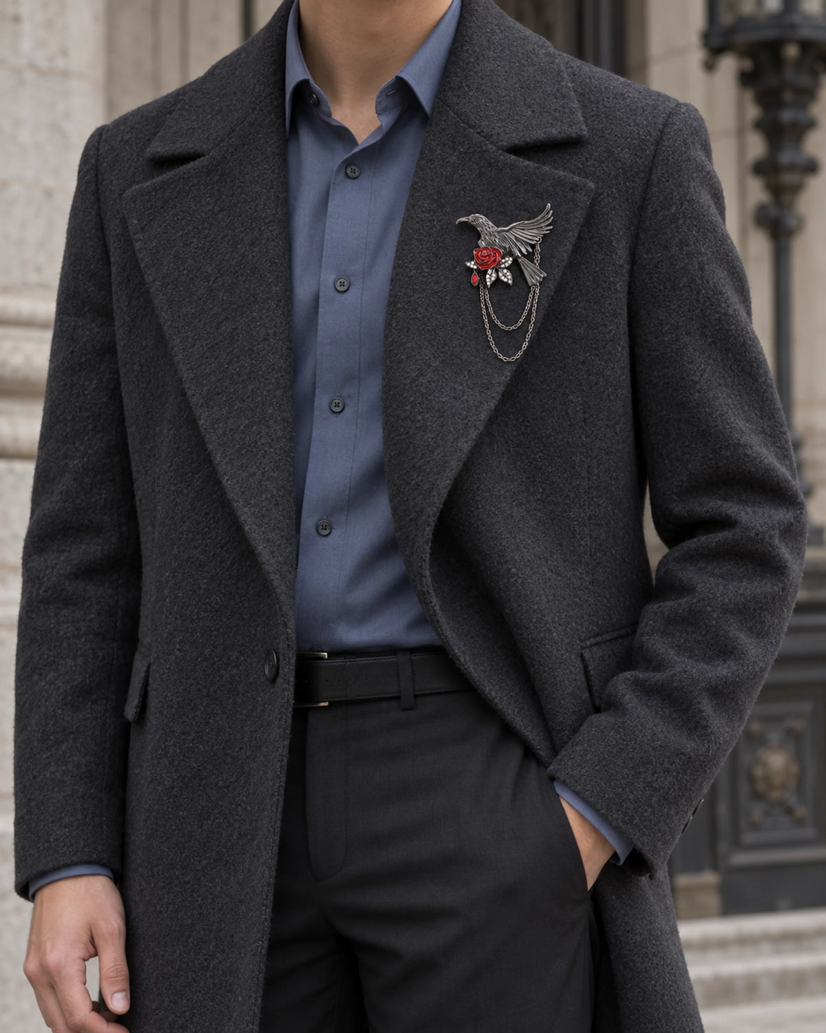 Noctra bird and rose brooch on a charcoal coat over a blue shirt