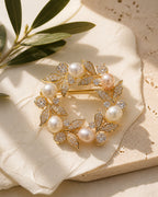 Olea Freshwater Pearl Wreath Brooch resting on pale travertine and softly folded ivory silk