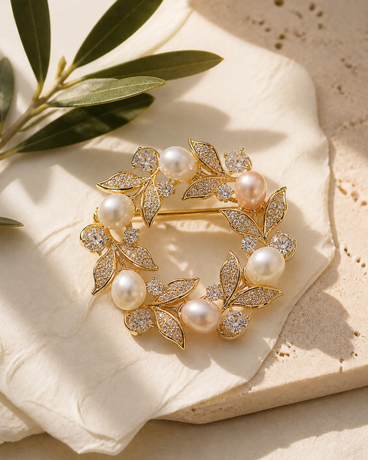 Olea Freshwater Pearl Wreath Brooch resting on pale travertine and softly folded ivory silk