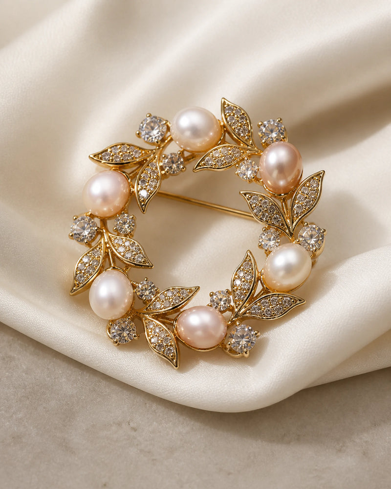 Angled studio view of the Olea brooch showing its open wreath form, freshwater pearls and pin construction