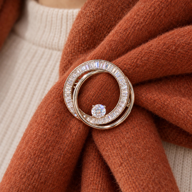 Two rust-colored scarf folds support the complete double-loop brooch at its small everyday scale.