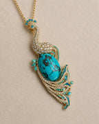 Macro view of the Pava peacock pendant's turquoise-tone patterned center, gold-tone frame and clear accents.