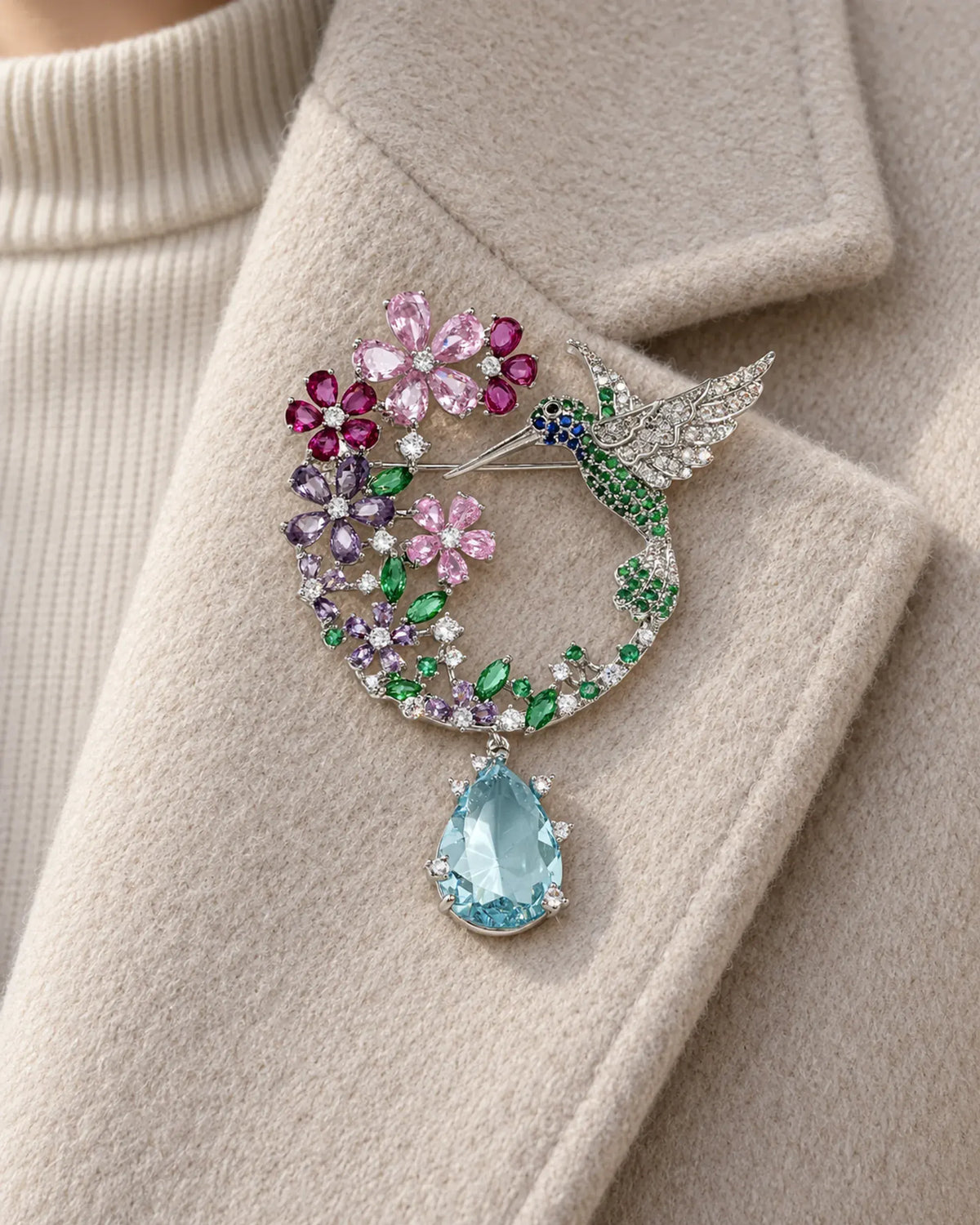 Pihla hummingbird brooch pinned to a broad oatmeal wool lapel