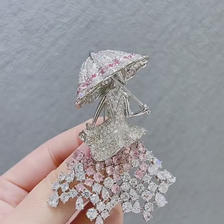 Noora Crystal Parasol Lady Brooch turning to show its blush-pink and clear stones, profile and pin-back construction