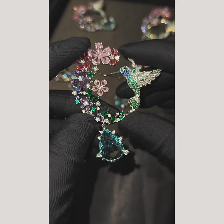 Silent film of Pihla’s hummingbird floral wreath brooch, showing the complete brooch, moving aqua drop and pin back.