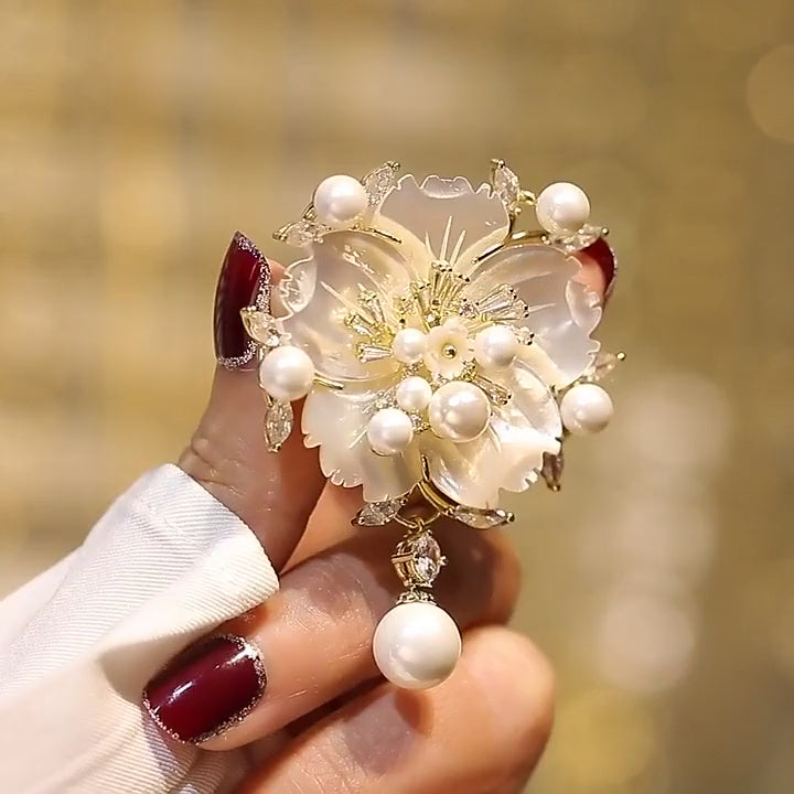 Linnea Pearl Shell Flower Brooch rotating to show natural shell petals, freshwater pearls, clear accents and its pin-back construction