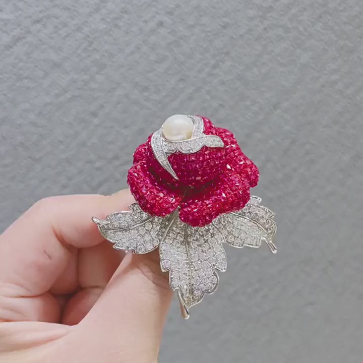 Aava Pearl Crystal Rose Brooch turning to show its blue and fuchsia crystal petals, pearl-like centre and pin-back construction