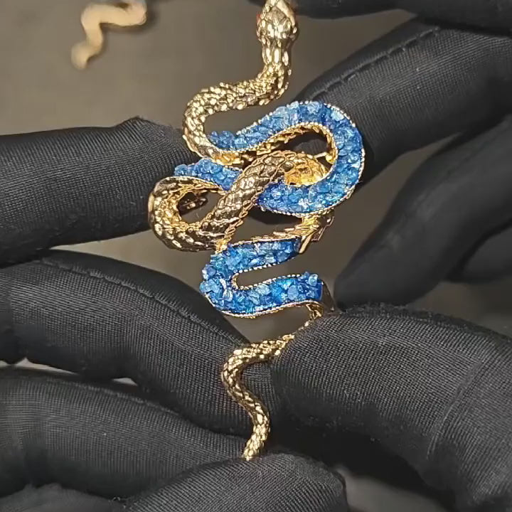 Sisu Color-Inlay Snake Brooch shown in motion with gold-tone scale texture, lake-blue colour inlay, red eye accents and pin-back profile