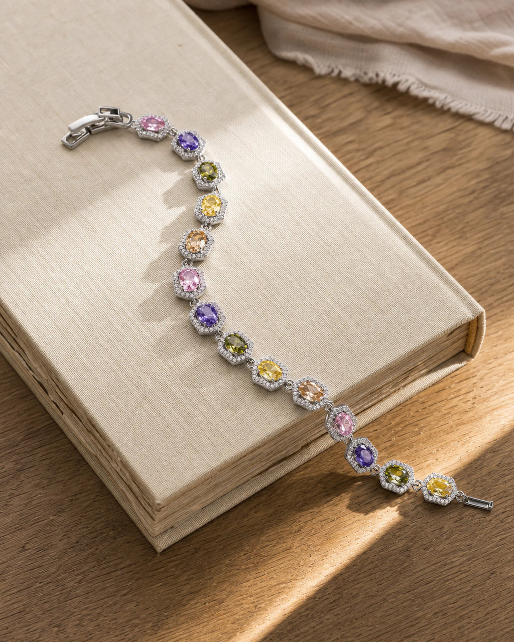 Prisma multicolor zircon bracelet resting in a realistic stone-and-linen still life.