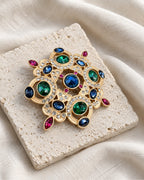 Ragna Multicolor Ornate Medallion Brooch — front view on a stone tile and ivory linen