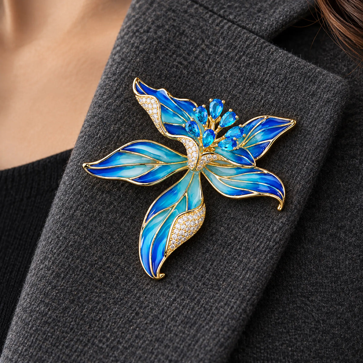 Blue Riina flower brooch pinned fully within a broad folded charcoal wool lapel.