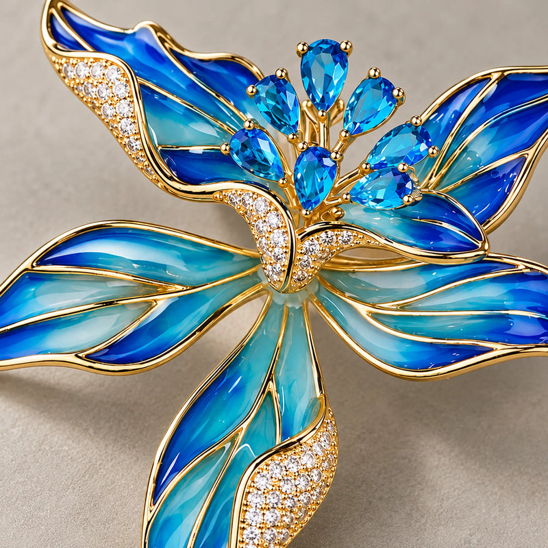 Macro of Riina in Blue showing pear-shaped zircon accents, clear pavé and gold-outlined enamel petals.
