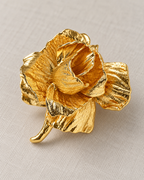 Rosana Sculpted Rose Brooch — oblique layered gold petal view on pale fabric