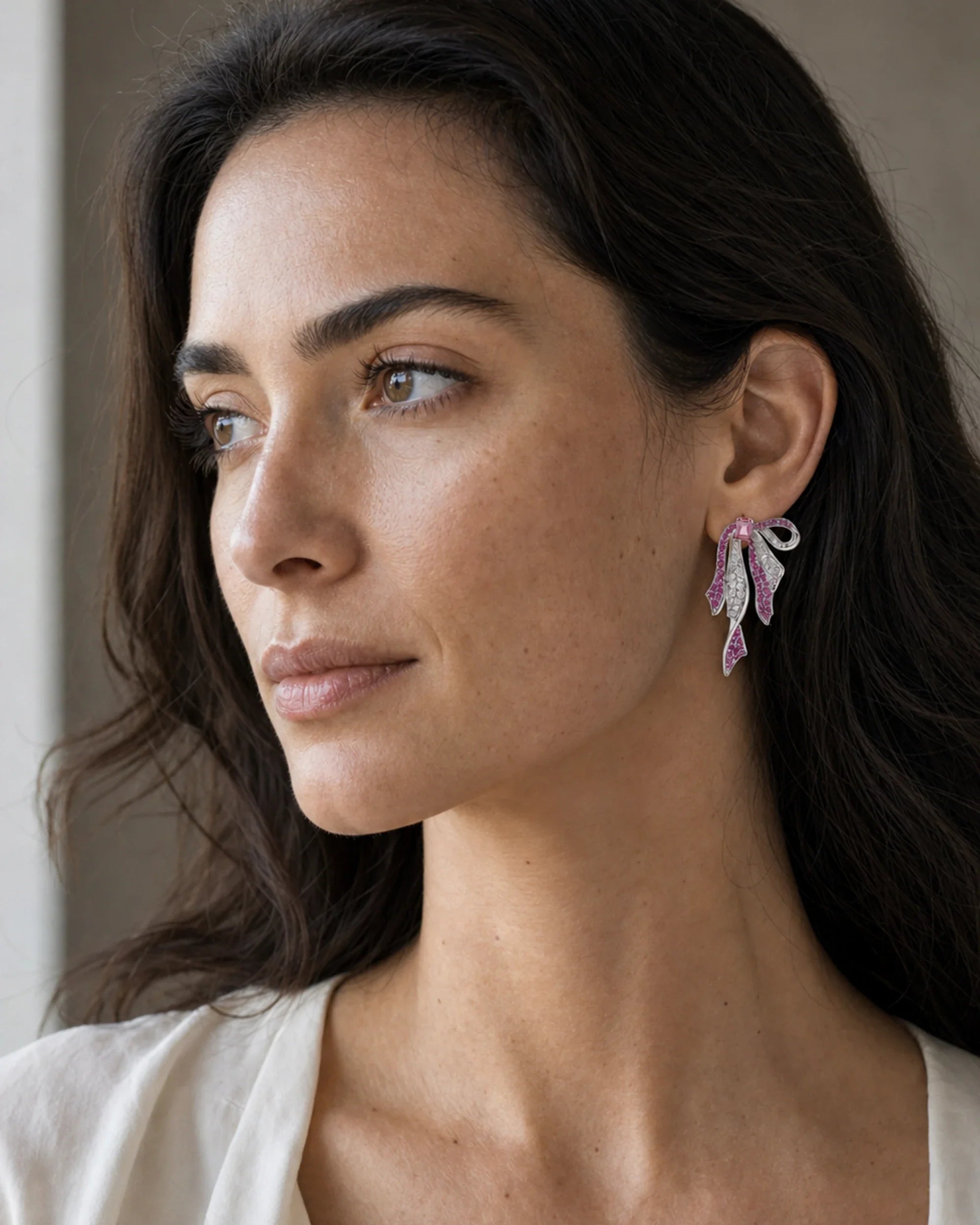 Close portrait of a woman wearing the Runa Ribbon Bow Drop Earring in White & Fuchsia