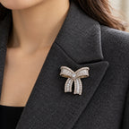 The small bow rests entirely within a charcoal wool folded lapel.