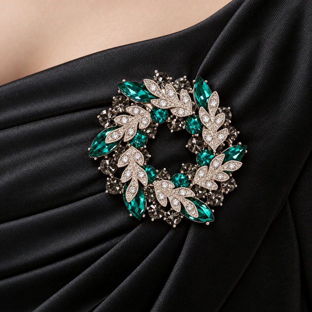 Green crystal leaf wreath brooch pinned to gathered black satin evening-dress fabric