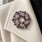 Purple crystal leaf wreath brooch pinned to an ivory jacket lapel in a close wearing view