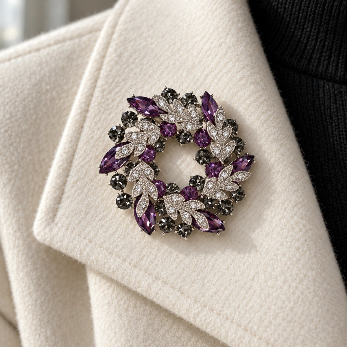 Purple crystal leaf wreath brooch pinned to an ivory jacket lapel in a close wearing view