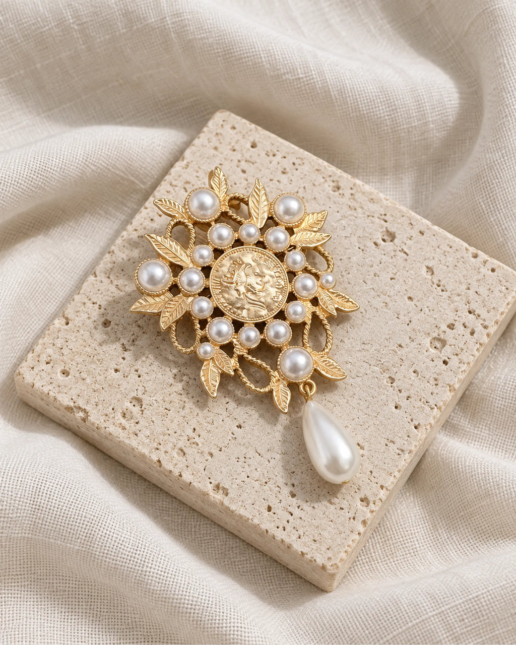 Signe Coin Medallion Drop Brooch — front view on a stone tile and ivory linen