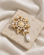 Signe Coin Medallion Drop Brooch — front view on a stone tile and ivory linen