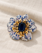 Sini Midnight Blue Crystal Flower Brooch resting on warm ivory linen