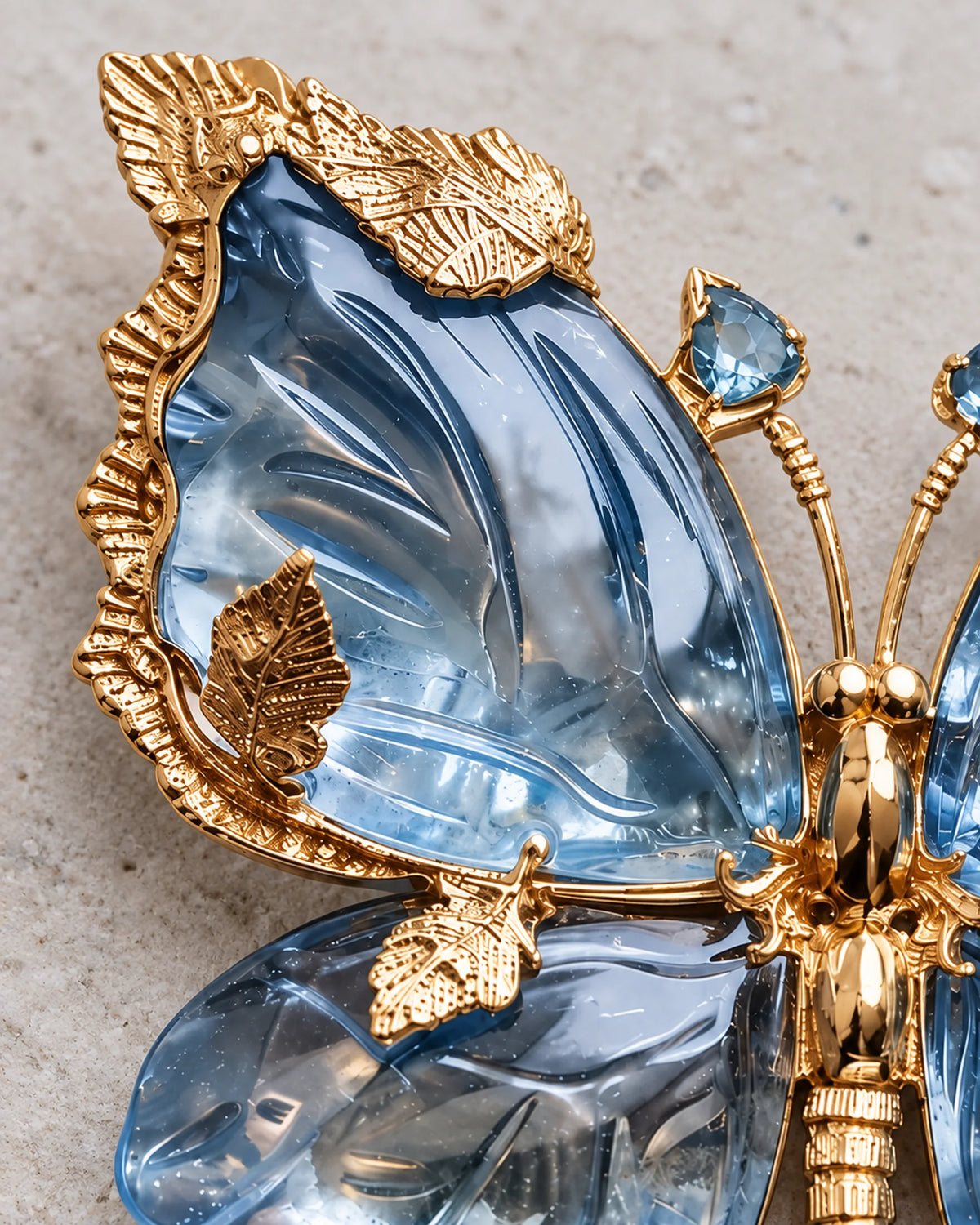 Close-up of Sini's sculpted blue crystal wing and textured gold-tone leaf settings.