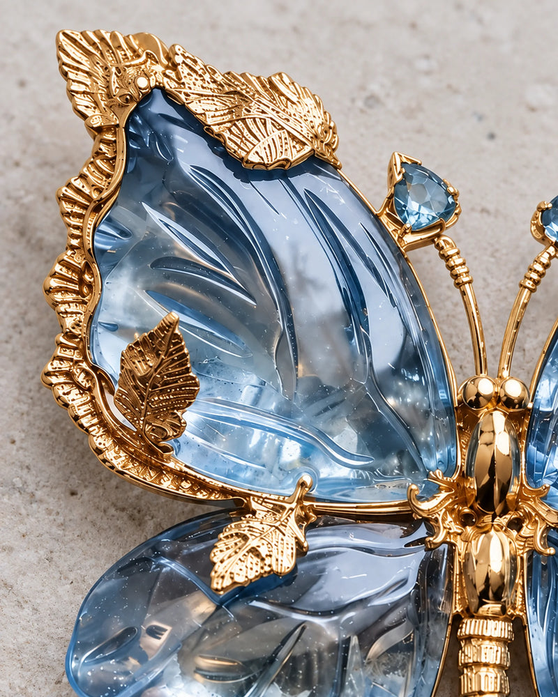 Close-up of Sini's sculpted blue crystal wing and textured gold-tone leaf settings.