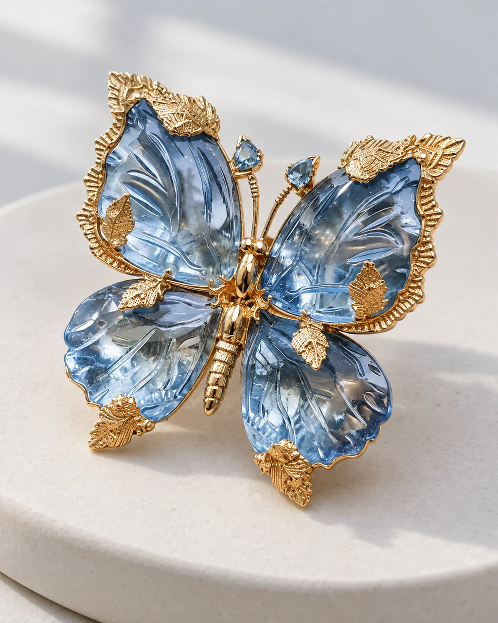 Sini blue crystal butterfly brooch in an angled front view on a pale ceramic display.