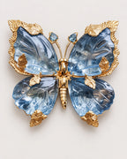 Sini blue crystal butterfly brooch with sculpted wings and gold-tone leaf settings, front view