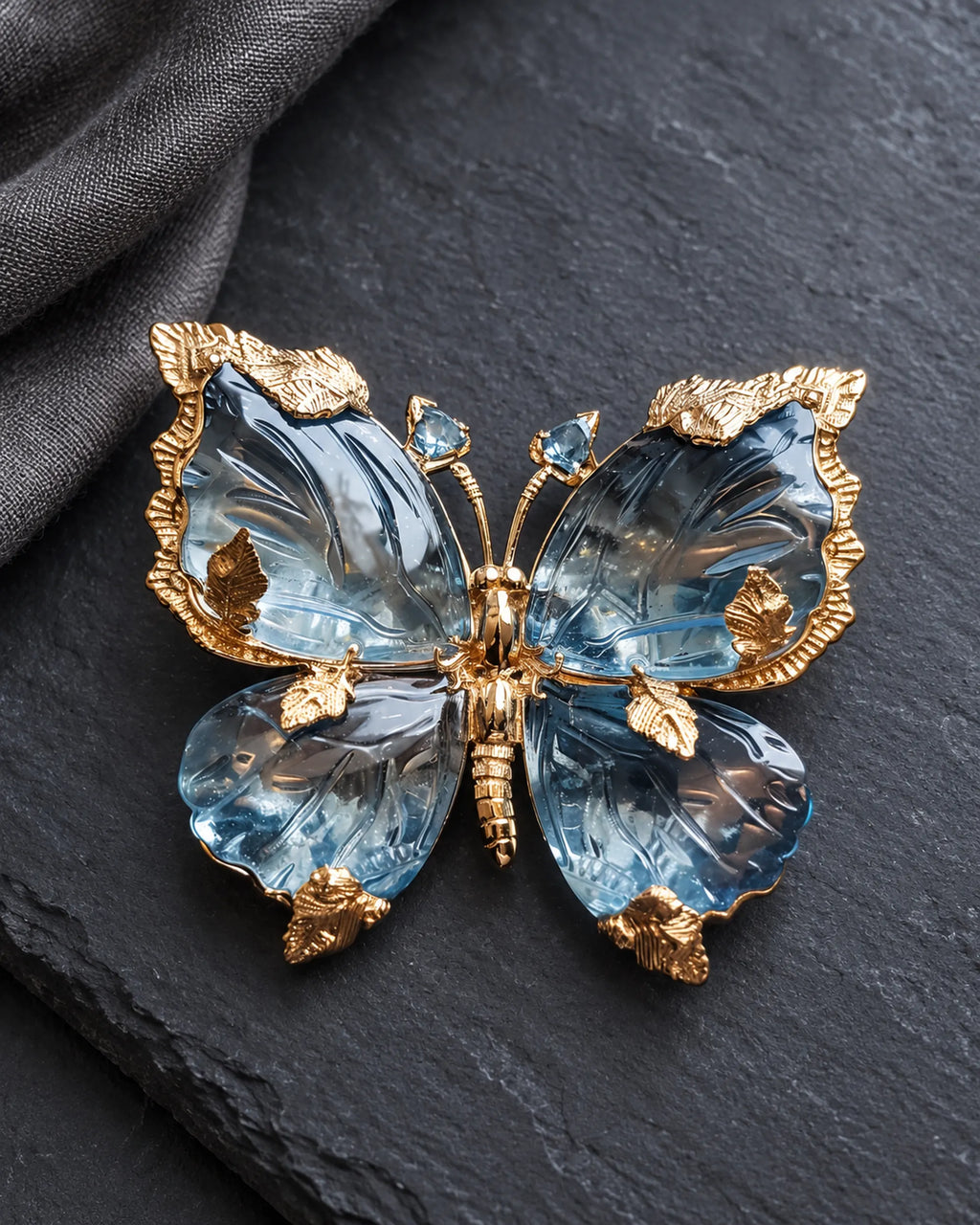 Sini blue crystal butterfly brooch on charcoal slate beside folded linen