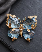 Sini blue crystal butterfly brooch on charcoal slate beside folded linen