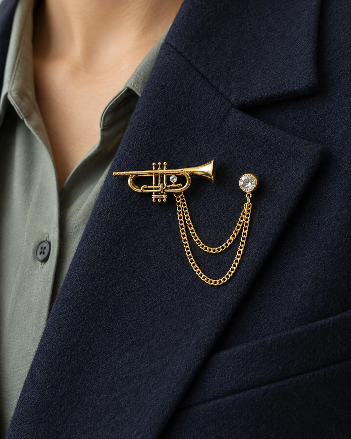 Sointu Trumpet Lapel Chain Brooch in gold-tone finish; close wearing view on a structured lapel