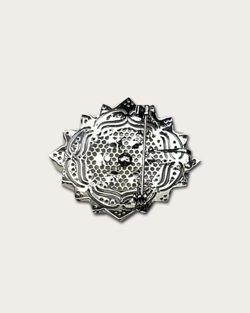 Rear view of the rosette brooch with its pierced metal back and long pin fastening.