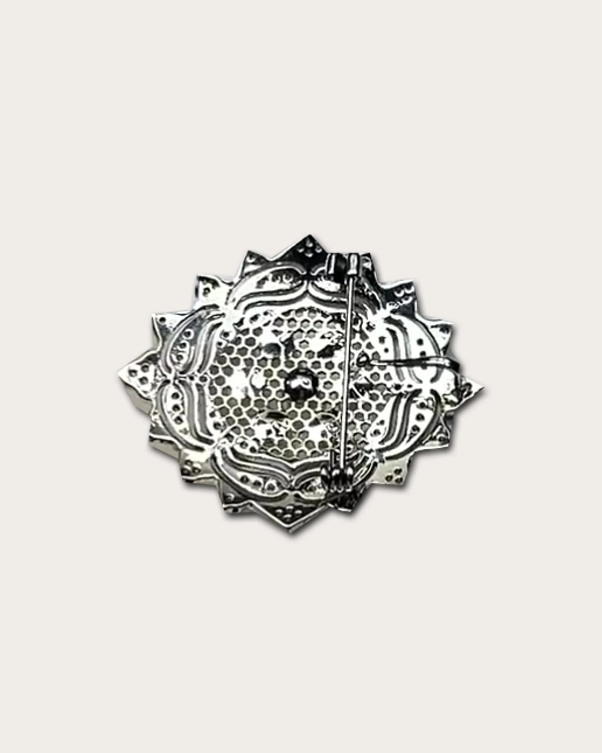 Rear view of the rosette brooch with its pierced metal back and long pin fastening.