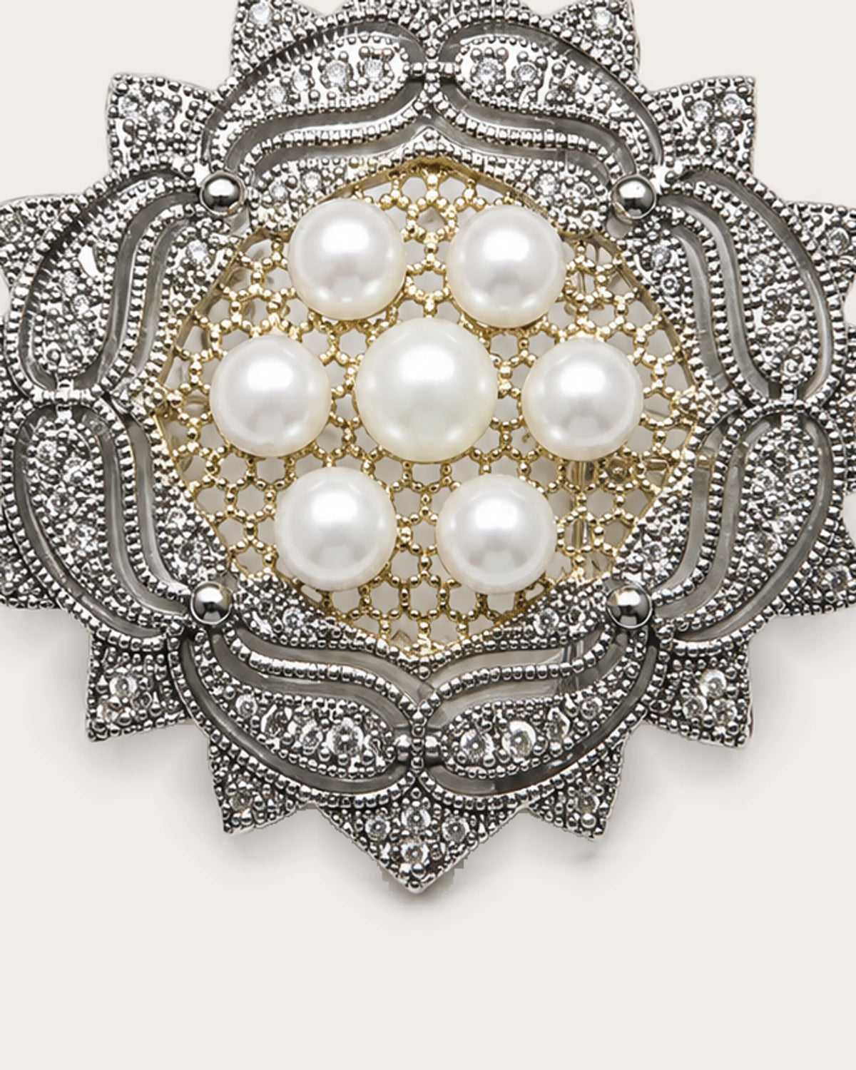 Close view of seven freshwater pearls and the rosette brooch’s pierced center and silver-tone scrollwork.
