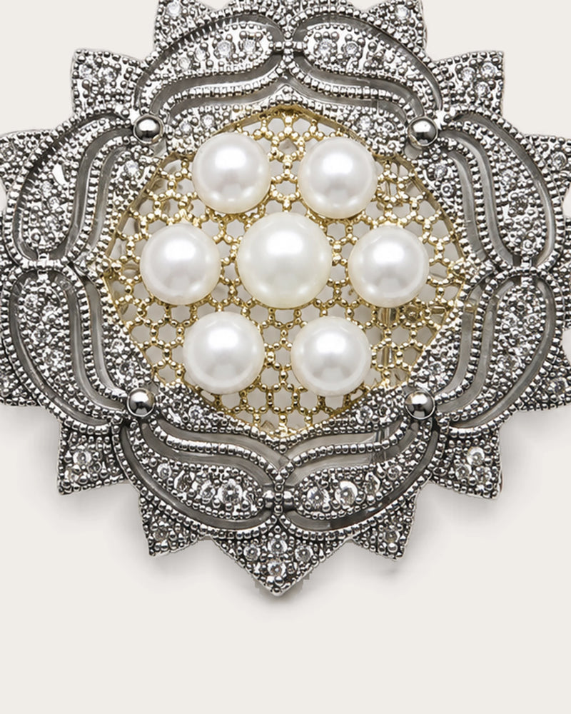 Close view of seven freshwater pearls and the rosette brooch’s pierced center and silver-tone scrollwork.