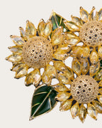 Detail of Suvia faceted yellow petals, raised gold-tone sunflower center and green leaf