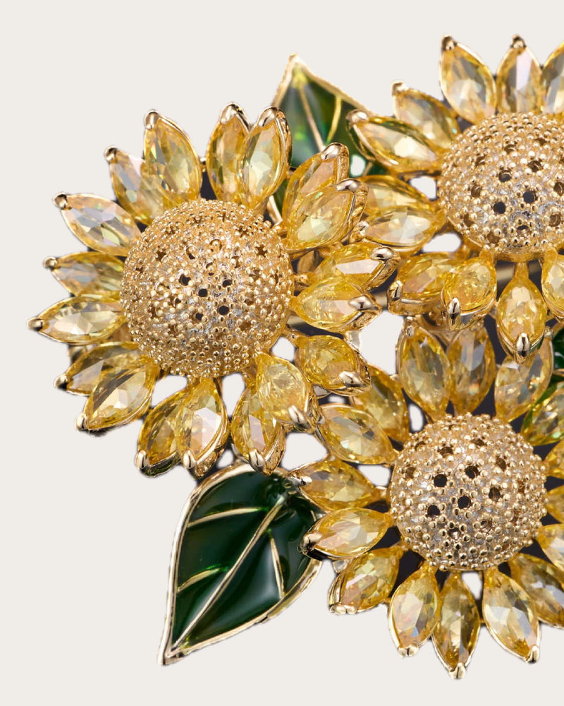 Detail of Suvia faceted yellow petals, raised gold-tone sunflower center and green leaf