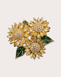 Suvia yellow crystal sunflower trio brooch with gold-tone centers and green leaves on a warm neutral background