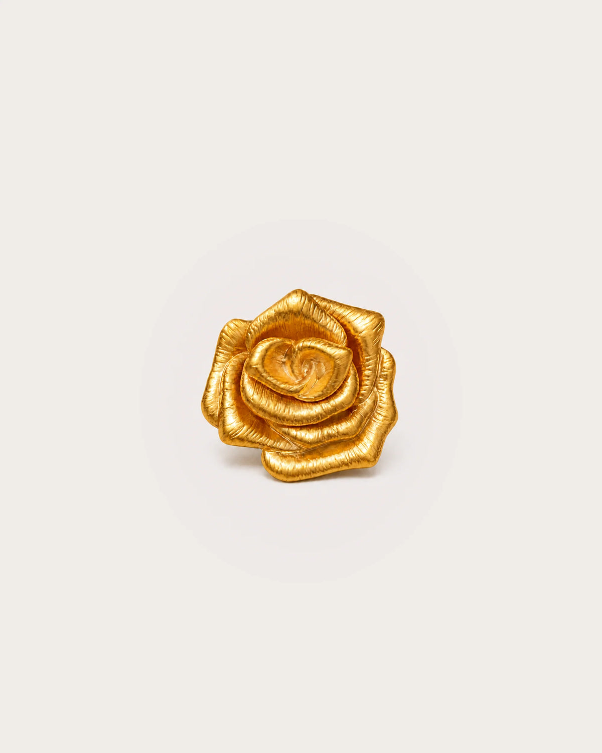 Taimi Mini Gold Camellia Brooch on a warm #F0EBE9 studio background with a natural contact shadow