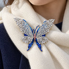 Tilda butterfly brooch fastened to a supported ivory wool scarf fold over navy clothing.