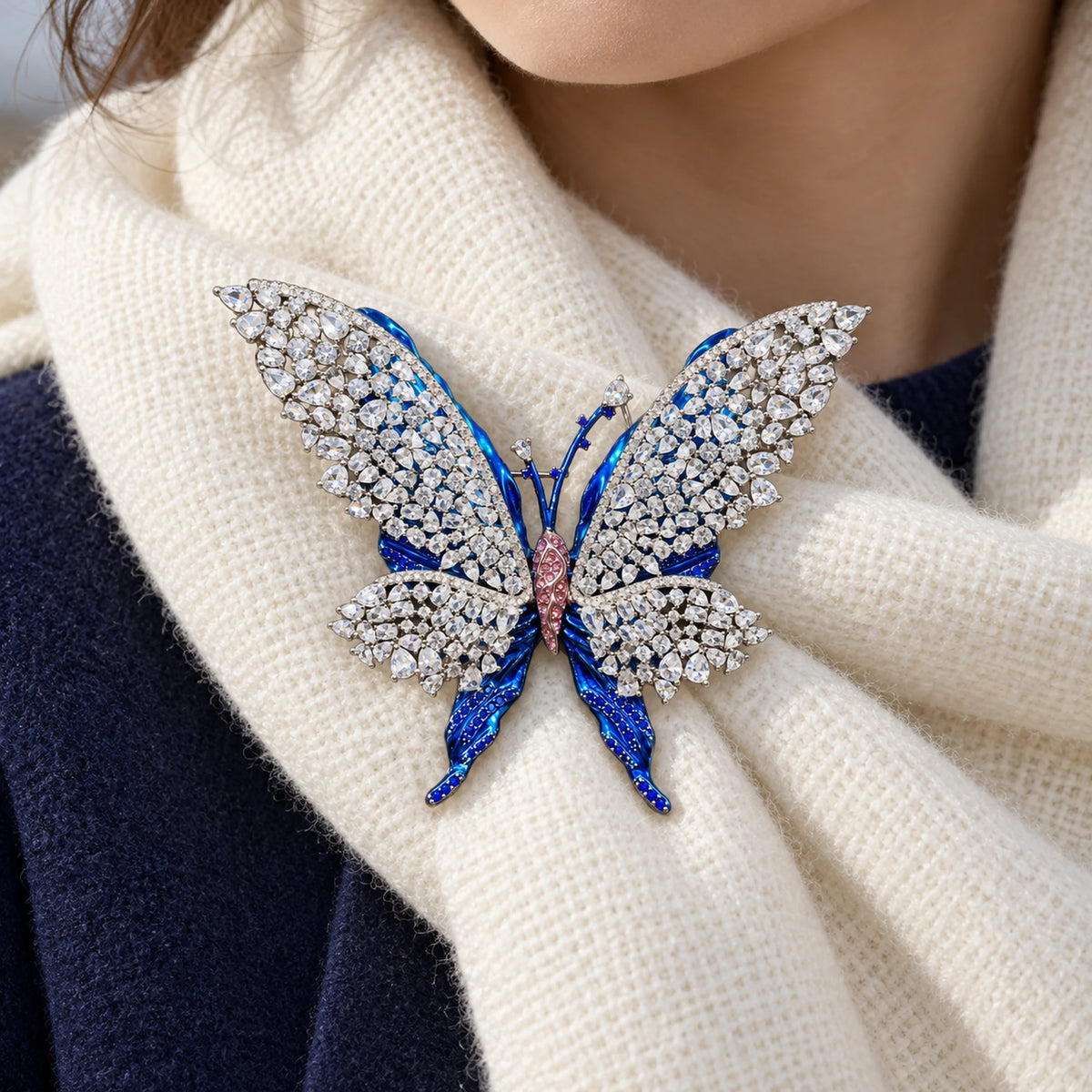 Tilda butterfly brooch fastened to a supported ivory wool scarf fold over navy clothing.