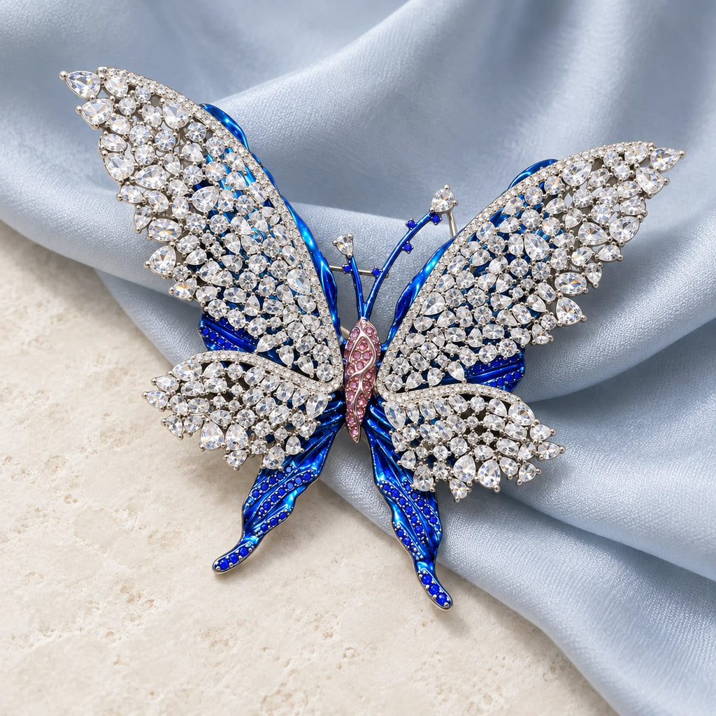 Tilda openwork butterfly brooch resting on pale blue-gray silk and ivory stone.